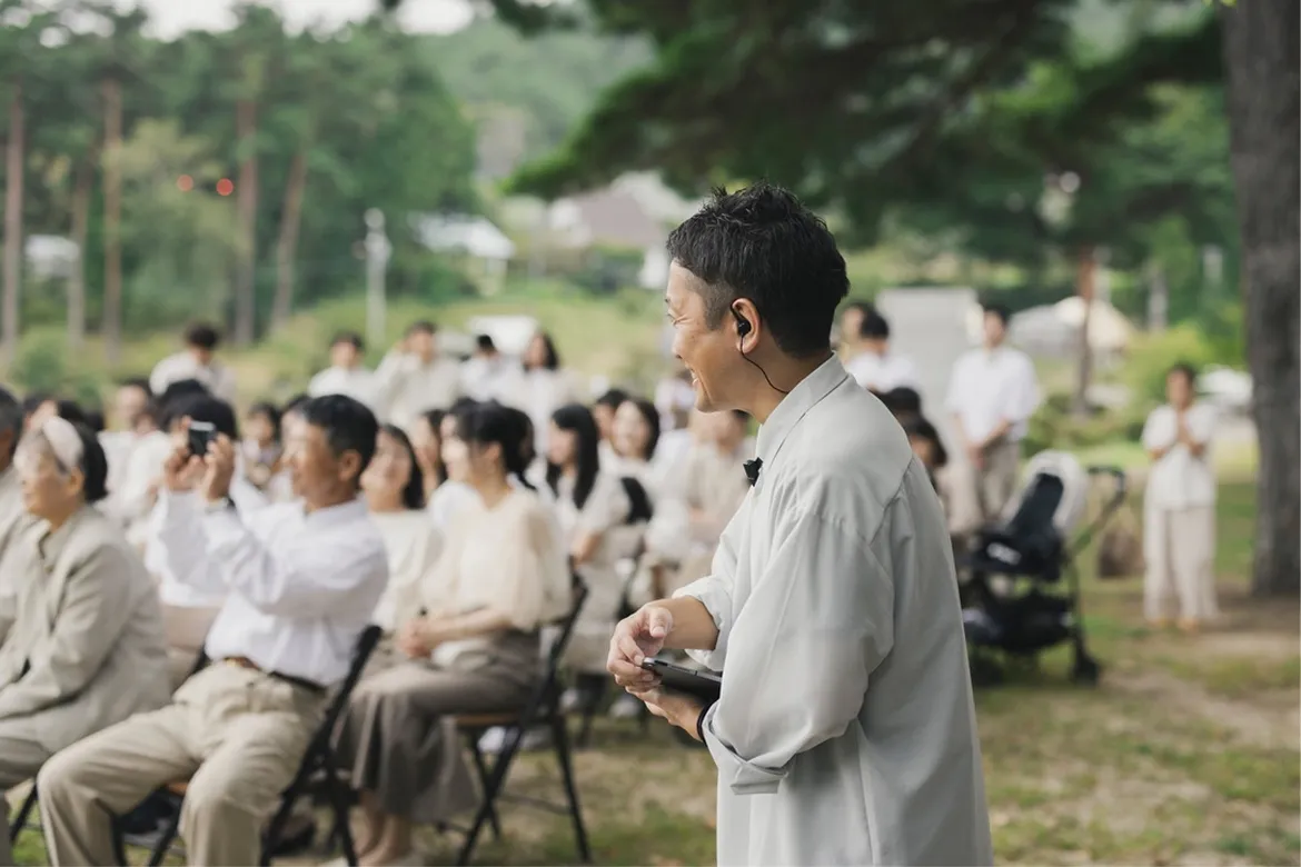 椅子に座る人達とそれを見て笑顔の代表