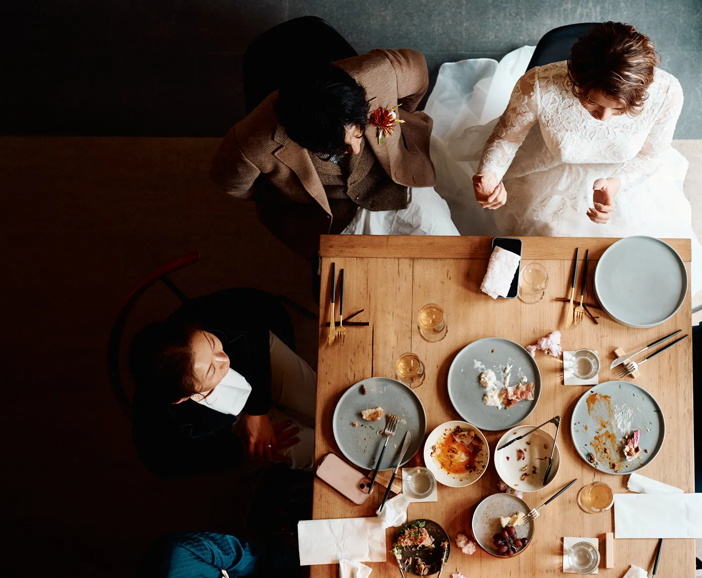 結婚披露宴のテーブルで、新郎新婦とゲストが食事を楽しんでいる様子を上から撮影した写真。